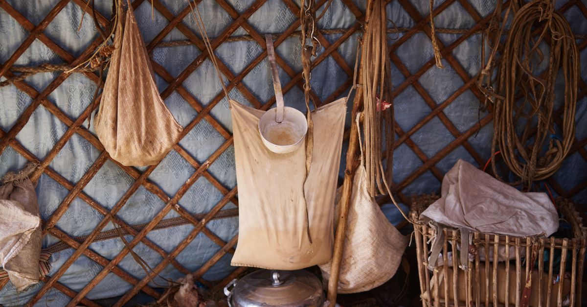 Inner part of authentic ger of Mongolian nomads with household utensils and fabric bags for storage near wooden frame of house under tent